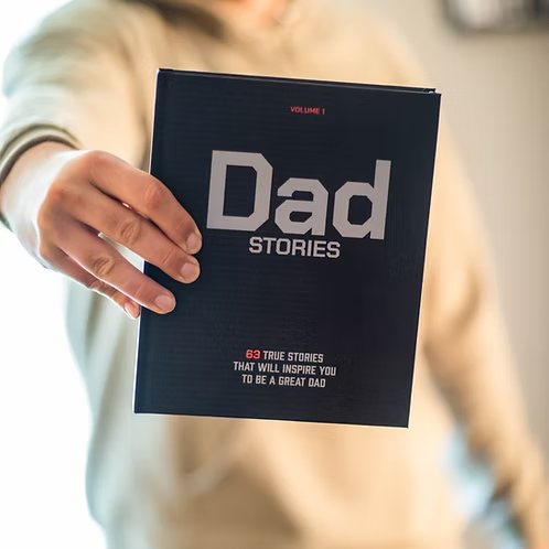 A hardcover copy of Dad Stories held out toward the camera
